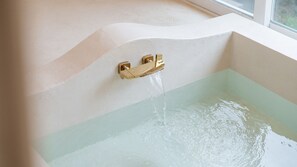 A bathtub with a gold faucet and a clear water flow. - Gyeongju Nenugnam20 Hanok Pension (Gyeongju)