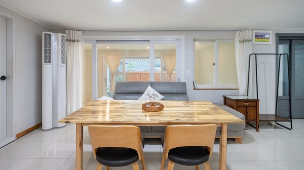 A dining area with a wooden table, two chairs, a sofa, and a small side table. - Gyeongju Nenugnam20 Hanok Pension (Gyeongju)