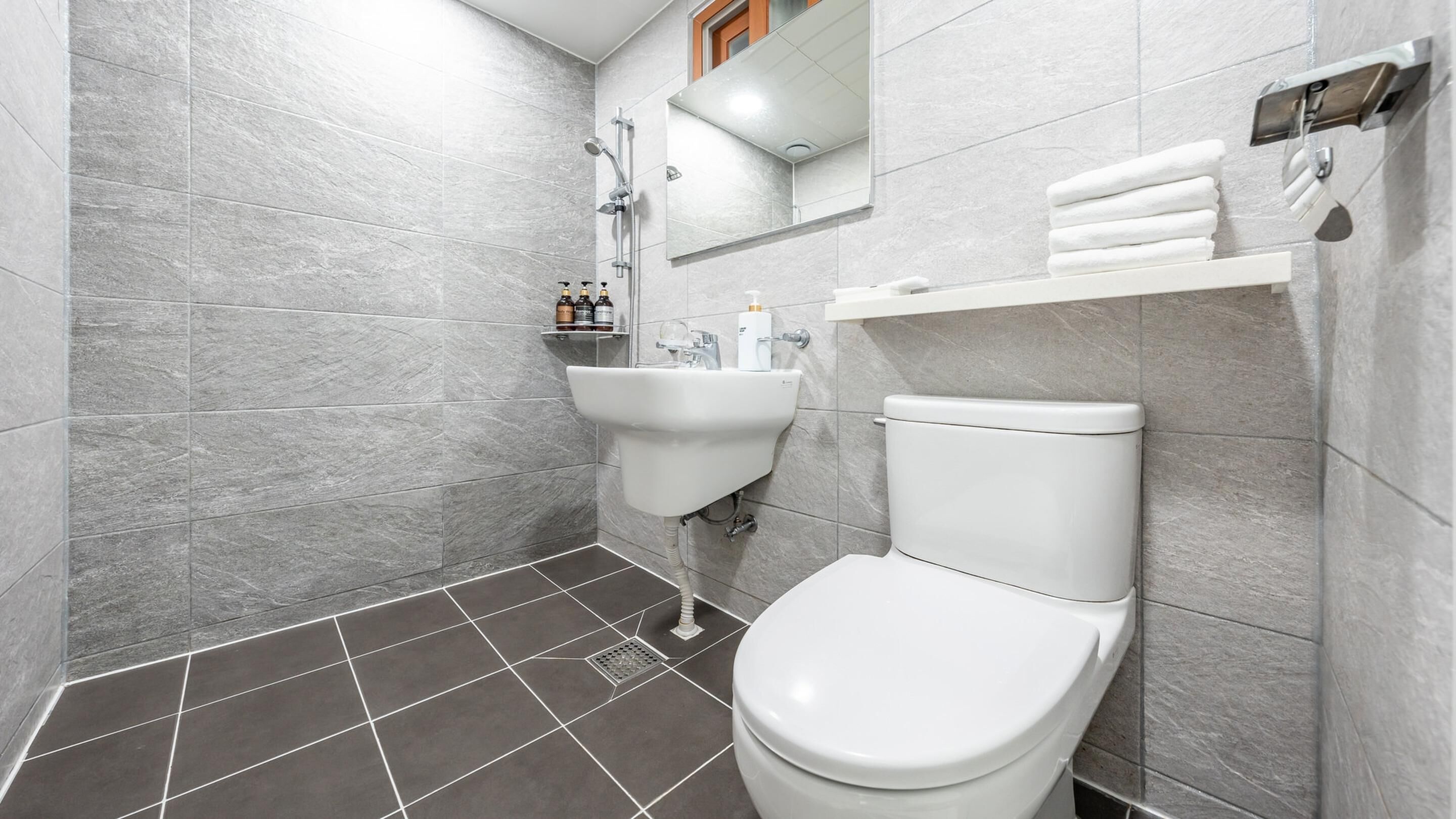 Une salle de bain moderne avec des toilettes blanches, un lavabo et une douche.