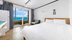 Une chambre d’hôtel avec un grand lit, un bureau et une vue sur l’océan.