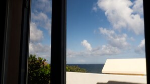 A view through a window with a clear sky and clouds, a white building, and greenery. - HIDDEN TREASURE (Point Blanche)