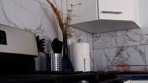 A kitchen with a stove, a white cabinet, and a marble backsplash. - HIDDEN TREASURE (Point Blanche)