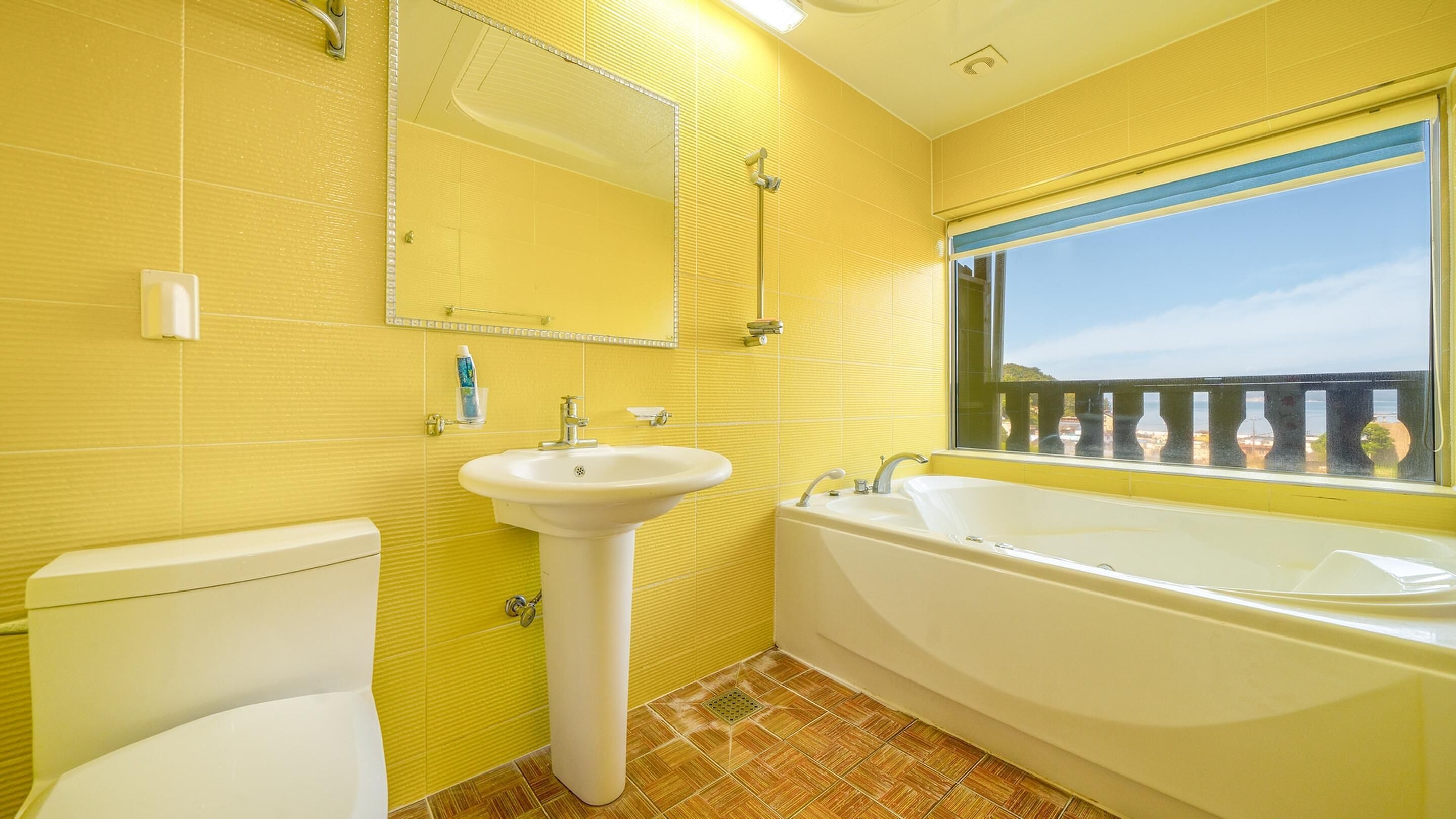 A bathroom with yellow walls, a white sink, a toilet, and a bathtub.