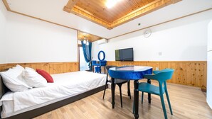 A room with a bed, a table with chairs, a TV, and a clock on the wall. - Geoje Gaonara Pension (Geoje)