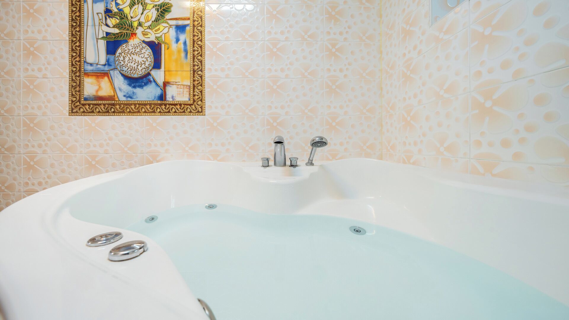 A bathroom with a freestanding bathtub, a wall-mounted sink, and a decorative tile backsplash.