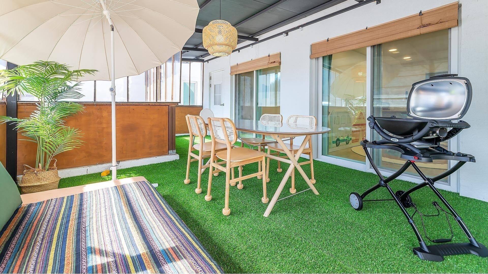 A patio with a round table and chairs, a grill, and a potted plant.