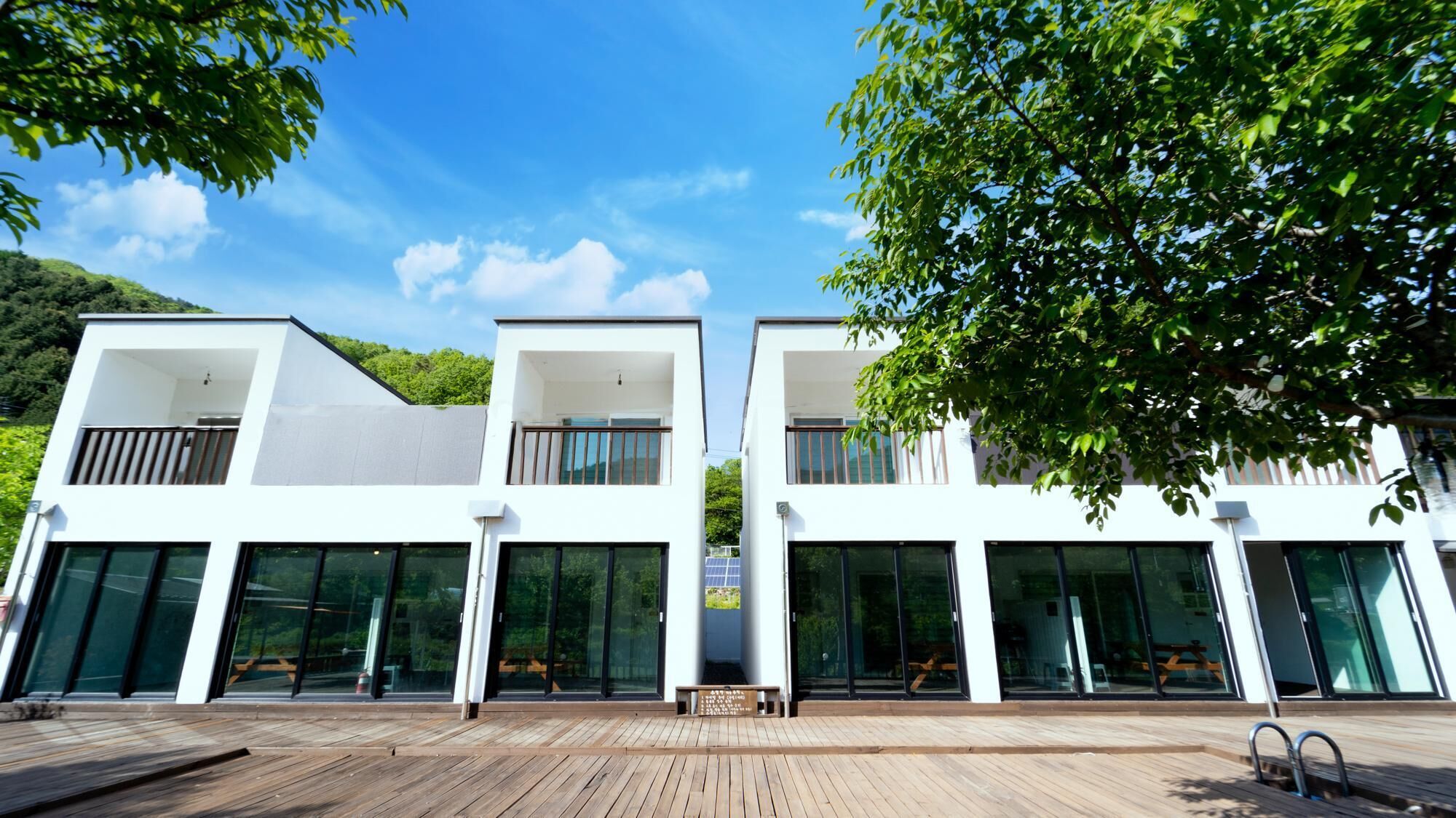 A modern two-story building with large glass windows and a wooden deck in front.