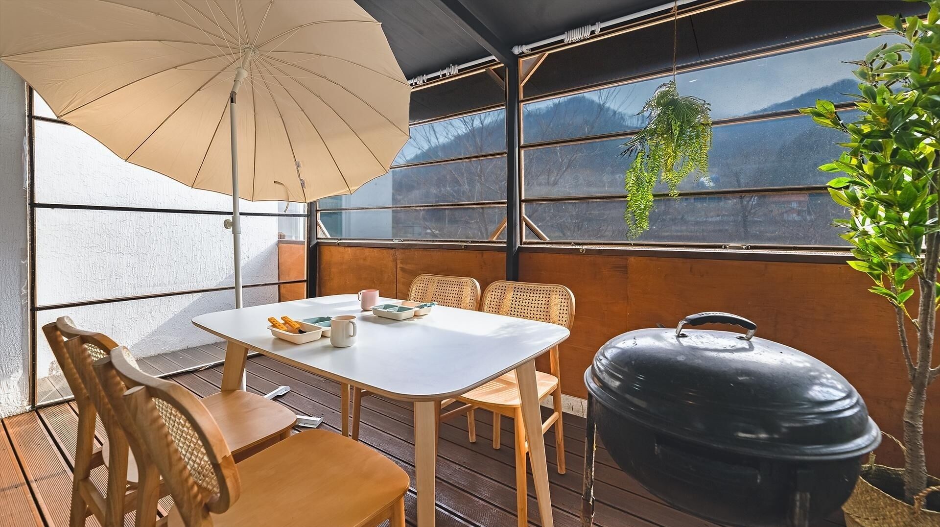 Un patio con mesa, sillas, una parrilla y una planta colgante.