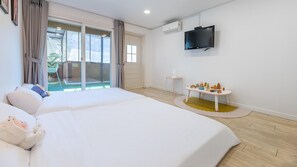 A hotel room with a large bed, a television mounted on the wall, and a small table with toys.