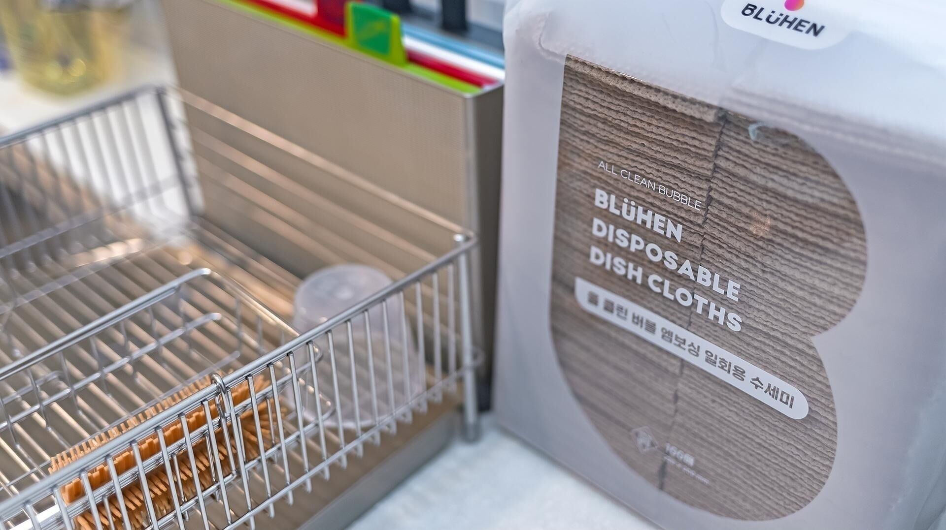 A kitchen with a dish rack and a package of disposable dish cloths.