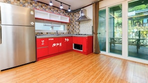 A kitchen with red cabinets, a stainless steel refrigerator, and a view of a patio through glass doors. - Gapyeong Yeoul Kids Pension (Gapyeong)