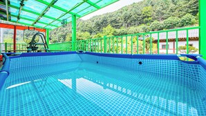 An indoor swimming pool with a clear view of a mountainous landscape through a green glass enclosure. - Gapyeong Yeoul Kids Pension (Gapyeong)