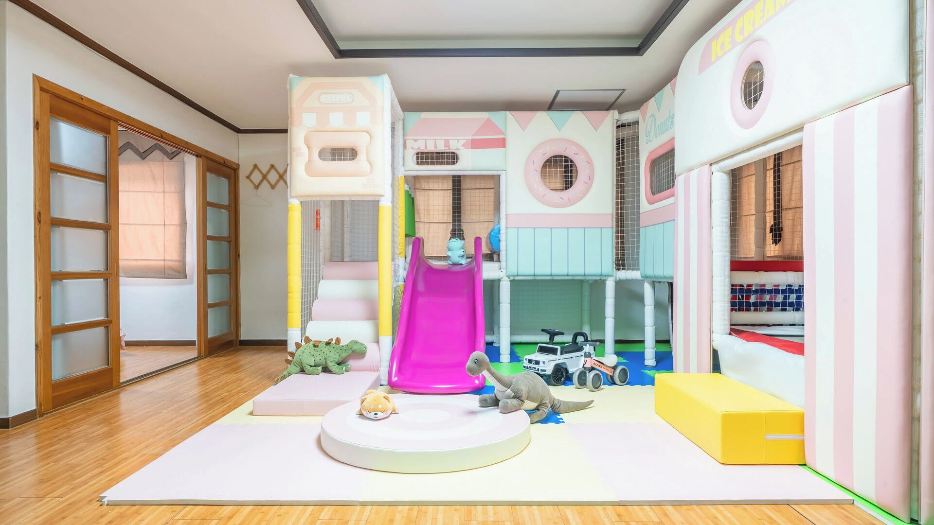 A playroom with a slide, play mats, and toy vehicles.
