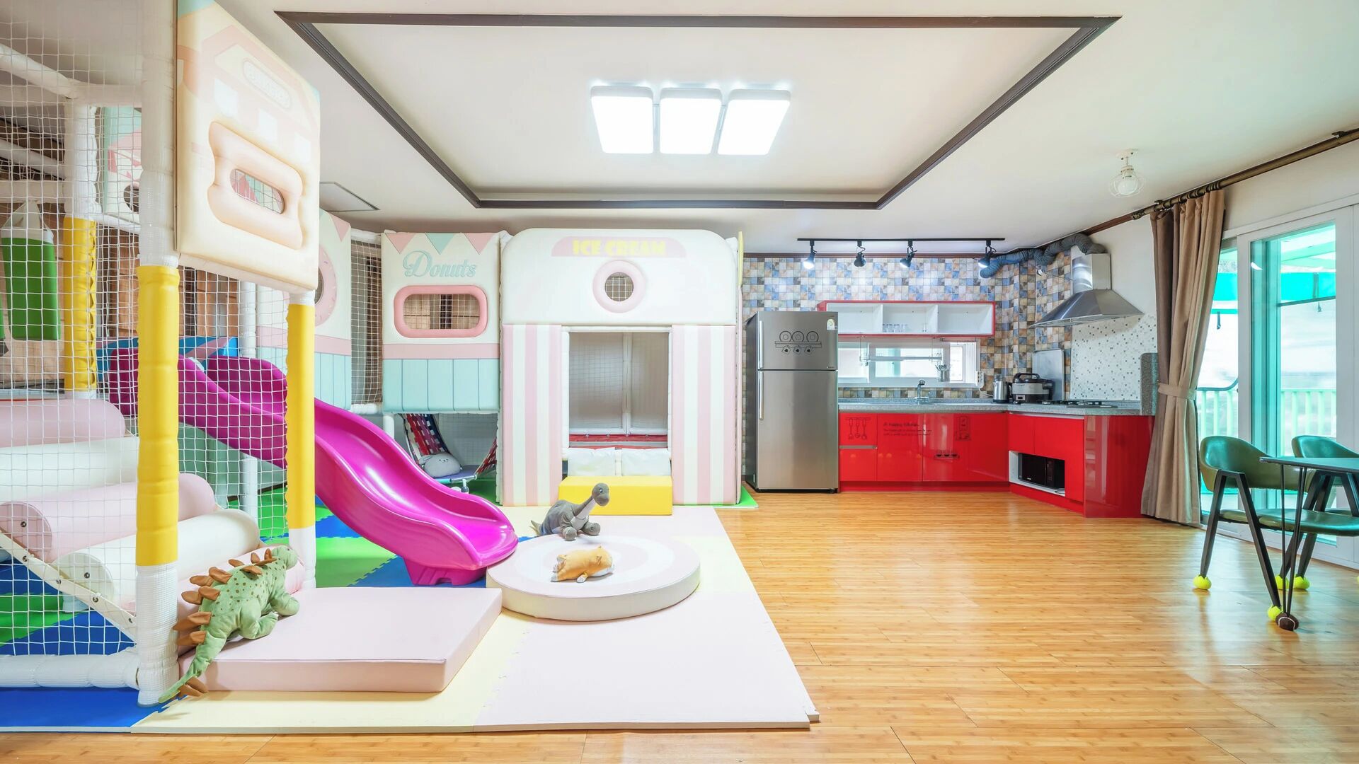 Uma área de recreação com um escorrega, um cercadinho e um dinossauro de brinquedo.