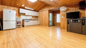 A spacious kitchen with wooden walls and floors, equipped with a refrigerator, oven, microwave, and a sink. - Gapyeong Yeoul Kids Pension (Gapyeong)