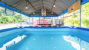 A covered swimming pool with a tiled floor, a red safety railing, and a blue canopy overhead. - Gapyeong Yeoul Kids Pension (Gapyeong)