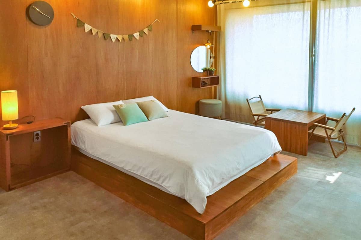 A modern bedroom with a wooden bed, bedside tables, a desk, and a chair.