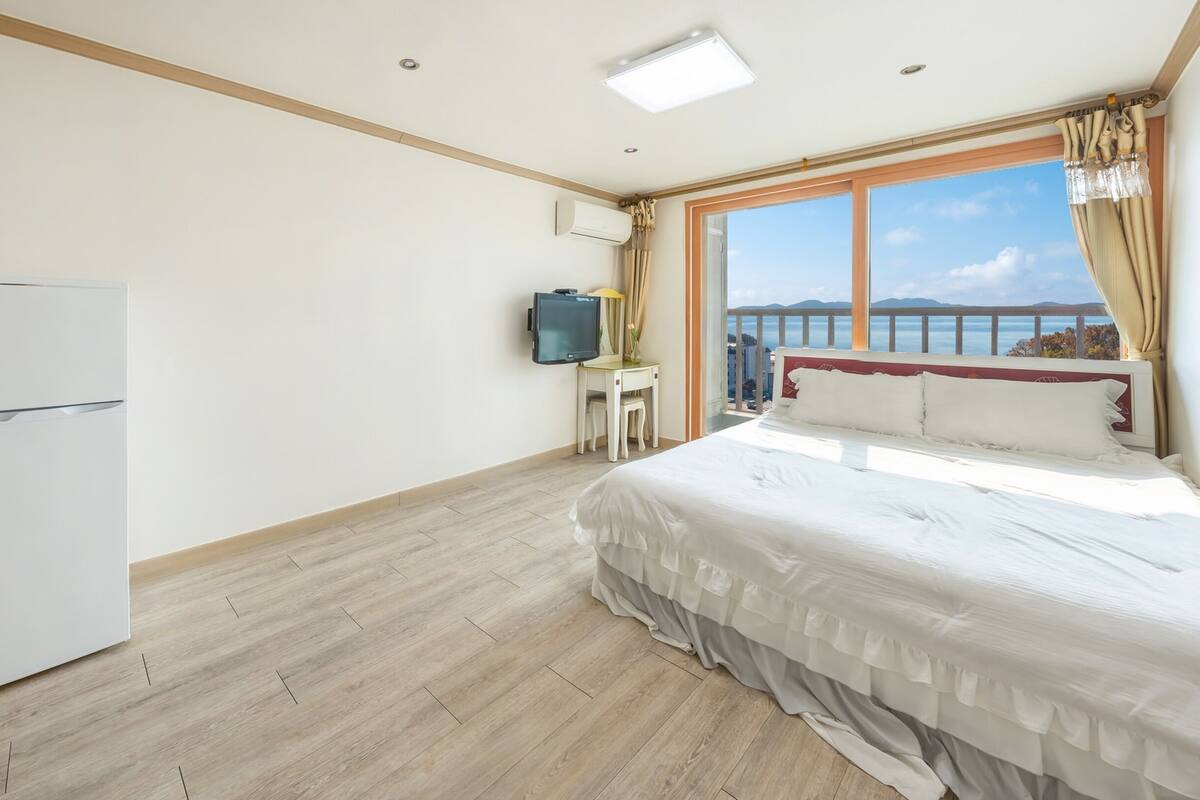 A hotel room with a bed, a TV, a small table, a microwave, and a kettle.