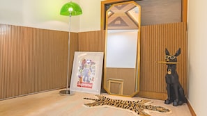 A room with a wooden panel wall, a green floor lamp, a framed artwork, a black statue, and a tiger skin rug. - Gapyeong Rondavill Pension (Gapyeong)