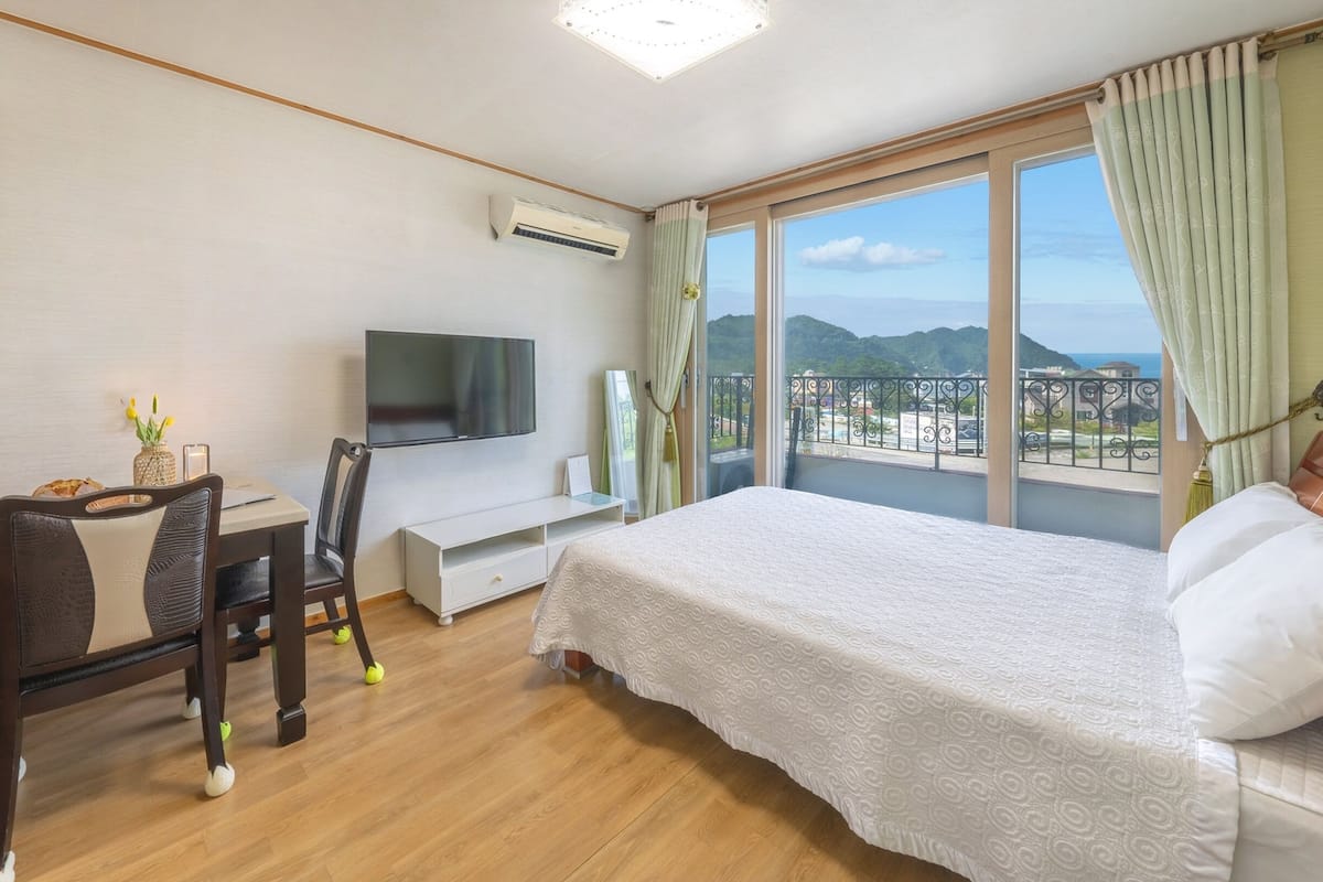 Une chambre d’hôtel comprenant un lit, un bureau avec une chaise, une télévision et un balcon avec vue sur les montagnes.