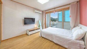 A bedroom with a bed, a TV, a bedside table, and a window with curtains. - Samcheok Yedaum Pension (Samcheok)