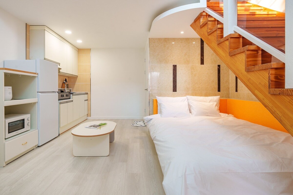 Une chambre d’hôtel compacte comprenant un coin cuisine, un lit et un escalier.
