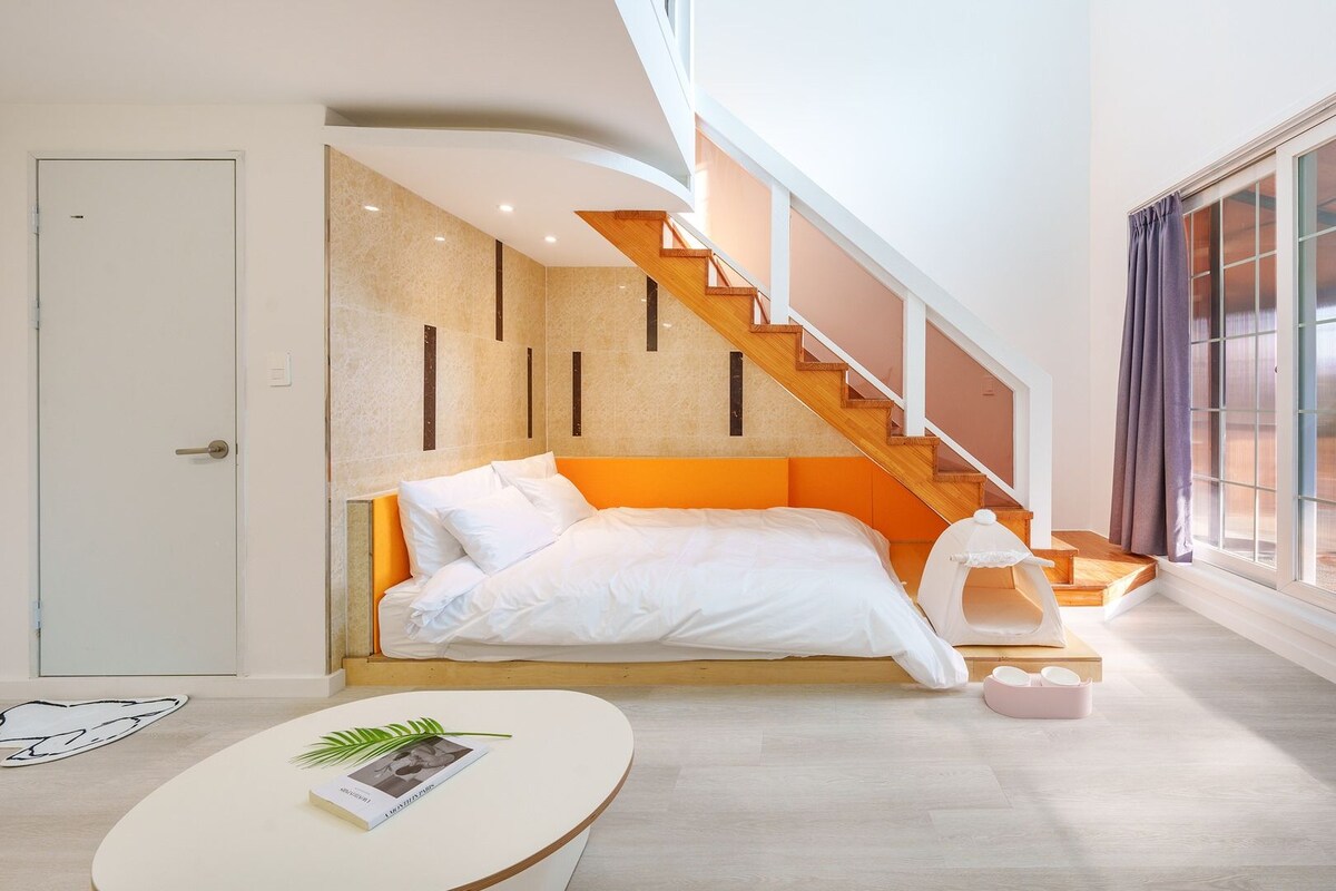 Une chambre d’hôtel moderne avec un lit, un escalier et une grande fenêtre.