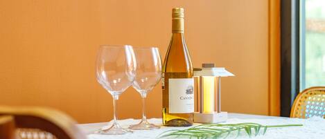 Een tafel met een fles Canyon Chardonnay en twee lege wijnglazen, een wijnwarmer en een kleine plant.