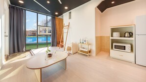 A modern hotel room with a large window, a dining table, a small play area, and a kitchenette. - Gapyeong Santa Maria Dog-friendly Privat (Gapyeong)