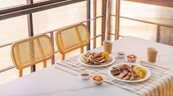 A dining table with plates of food, two chairs, and a window with a view. - Gapyeong Santa Maria Dog-friendly Privat (Gapyeong)