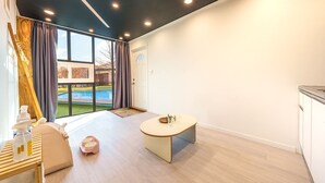 A modern living room with a pool view, a dining area with a table and chairs, and a kitchen area. - Gapyeong Santa Maria Dog-friendly Privat (Gapyeong)