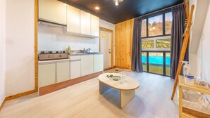 A compact kitchen with white cabinets, a stove, and a dining area with a table. - Gapyeong Santa Maria Dog-friendly Privat (Gapyeong)