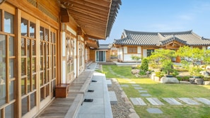 A traditional Korean-style building with wooden architecture, a stone pathway, and a well-maintained garden.