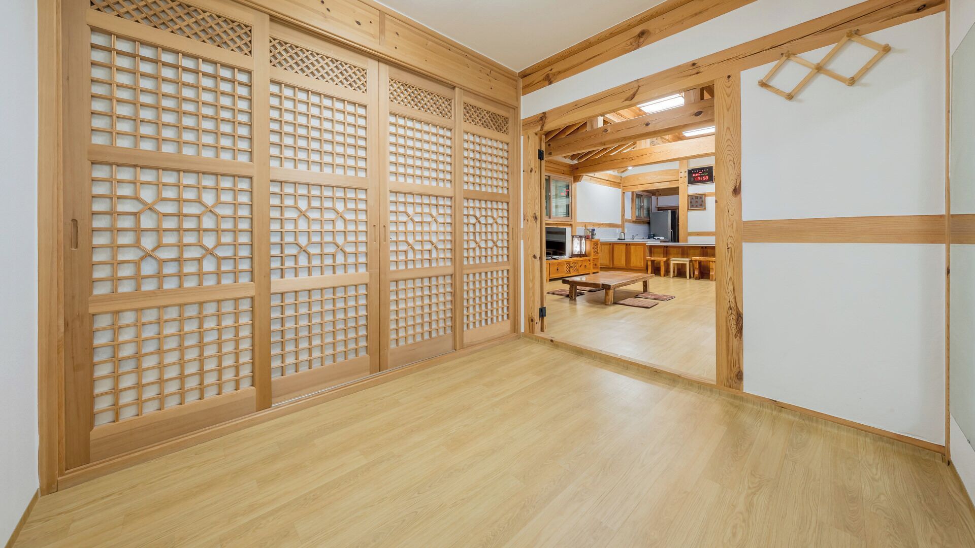 Un interior japonés tradicional con puertas correderas, suelo de madera y una zona de cocina con mesa de comedor.