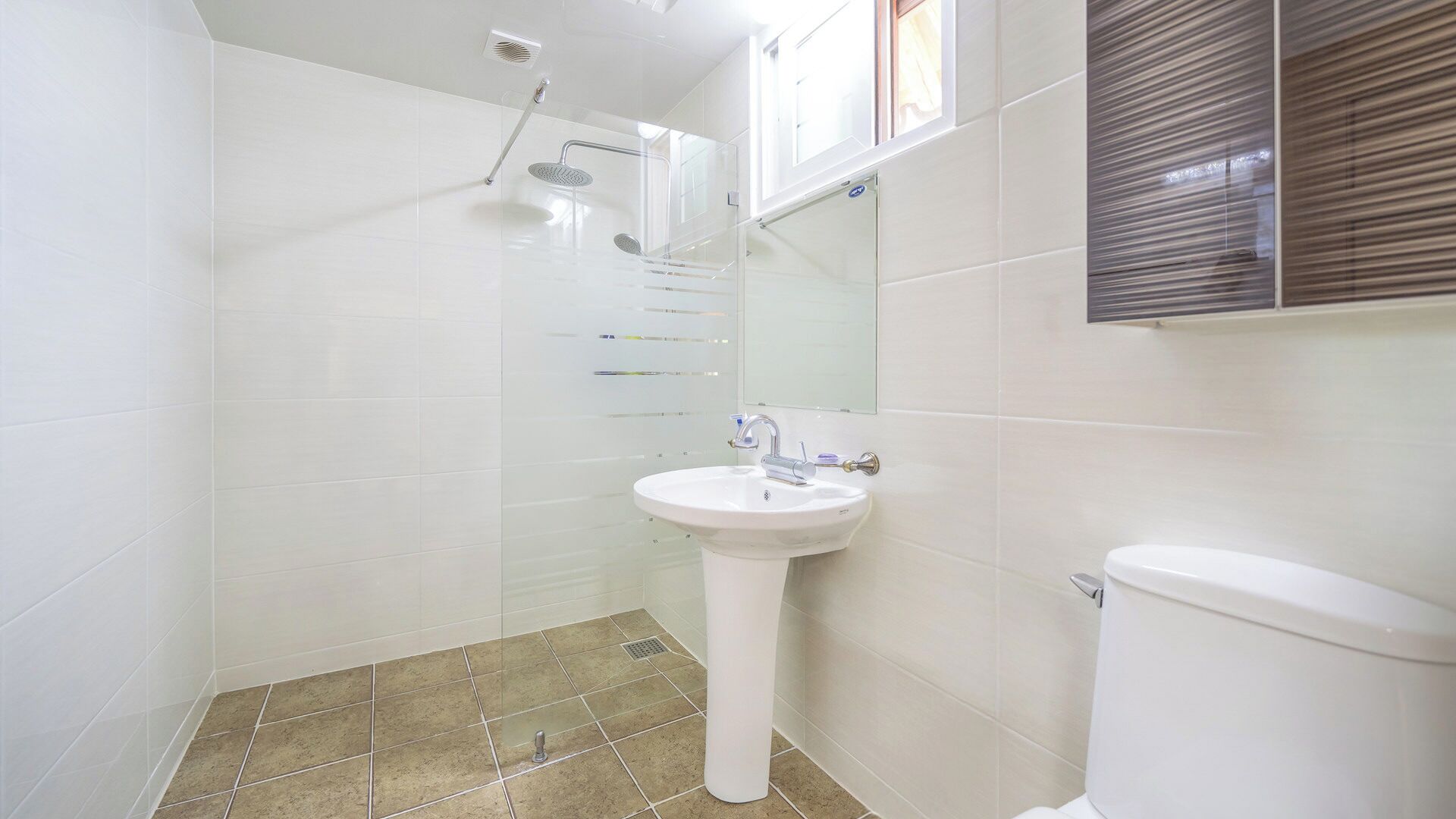 Een badkamer met douche, wastafel en toilet.