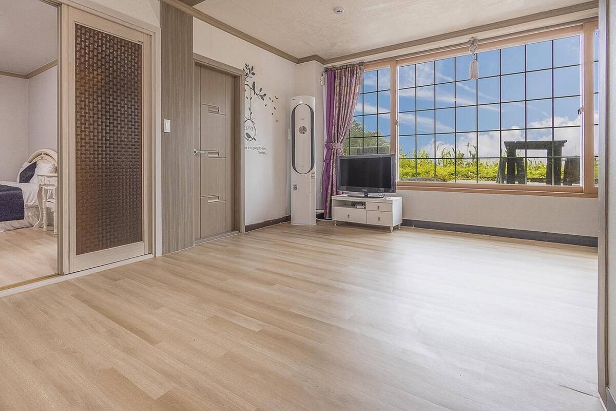 Une chambre avec un lit, une télévision et une fenêtre donnant sur un paysage verdoyant.