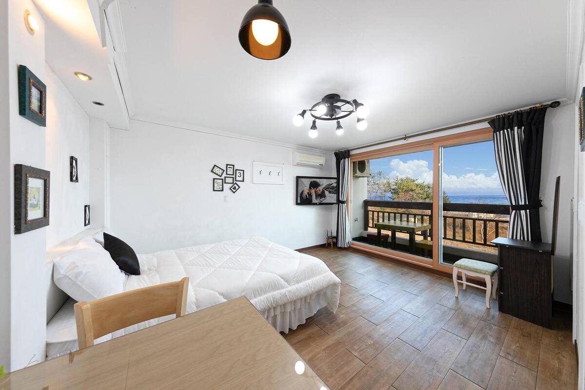 Une chambre à coucher avec un lit, une table en bois et un balcon offrant une vue.
