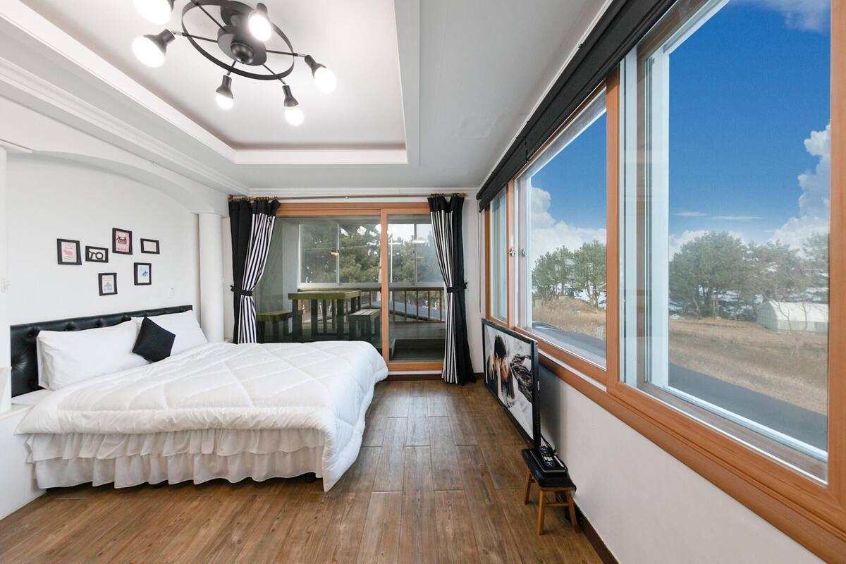 Une chambre à coucher avec un lit, un luminaire au plafond, une fenêtre et une vue sur l’extérieur.