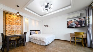A bedroom with a bed, a desk, a chair, a TV, and a decorative wall panel. - Gangneung Undukmaru Pension (Gangneung)