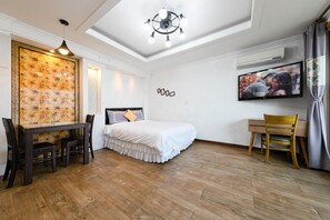 Une chambre à coucher comprenant un lit, un bureau, une chaise, un téléviseur et un panneau décoratif mural.