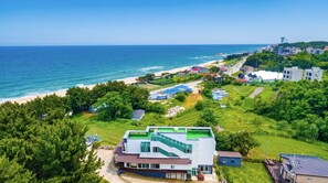 A coastal residential area with a prominent building featuring a green roof and a staircase. - Gangneung Undukmaru Pension (Gangneung)