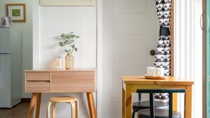 A small, clean room with a wooden desk, a stool, a table with a chair, and a patterned curtain. - Gangneung Undukmaru Pension (Gangneung)