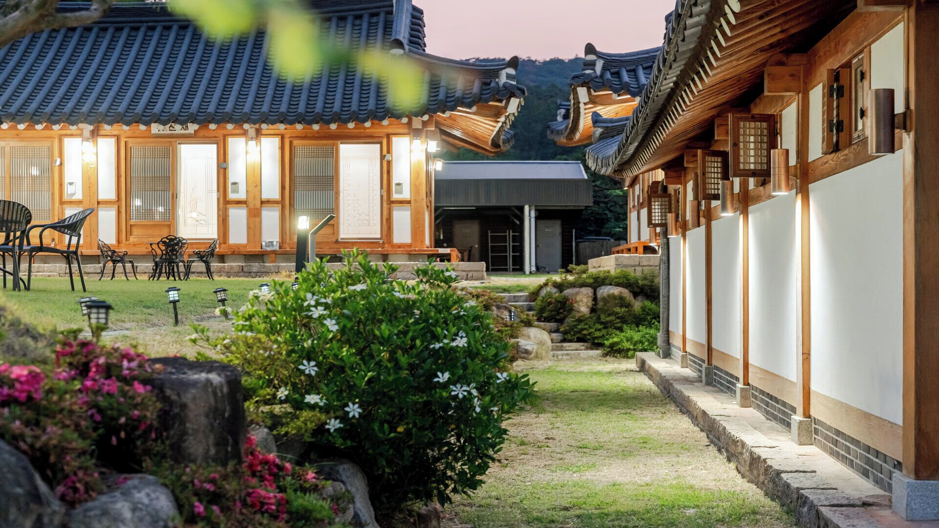 Un bâtiment de style japonais traditionnel, doté d’un jardin, d’une architecture en bois et d’un espace détente avec des chaises.