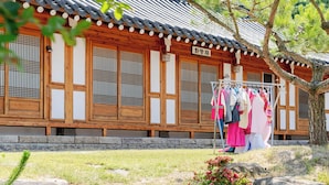 A traditional wooden building with a tiled roof, a clothesline with garments, and a stone base.