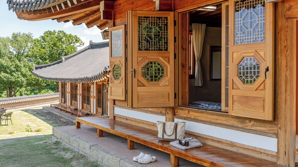 Un edificio de madera tradicional con puertas abiertas, un banco en el exterior y una vista de un tejado típico.