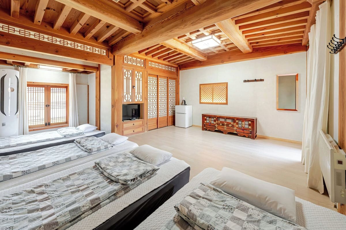 A traditional Japanese-style room with tatami flooring, a low ceiling with wooden beams, and a sliding door with a geometric pattern.