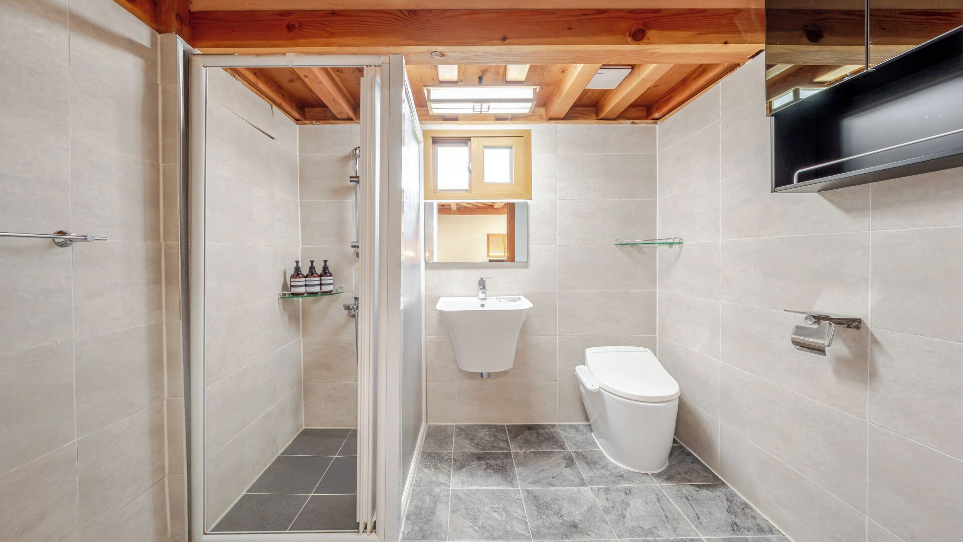 A bathroom with a shower, toilet, sink, and mirror.