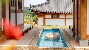 A traditional Korean-style building with a small indoor pool and a wooden deck.