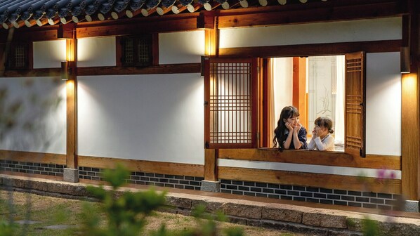Un bâtiment japonais traditionnel, avec des poutres en bois, des murs blancs et une fenêtre ornée d’un treillis en bois.