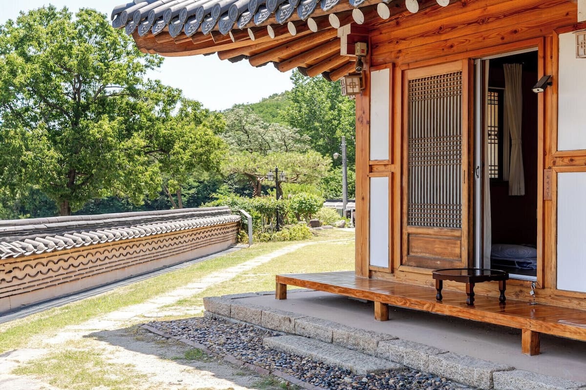 A traditional wooden building with a tiled roof, a wooden bench outside, and a stone pathway leading to it.